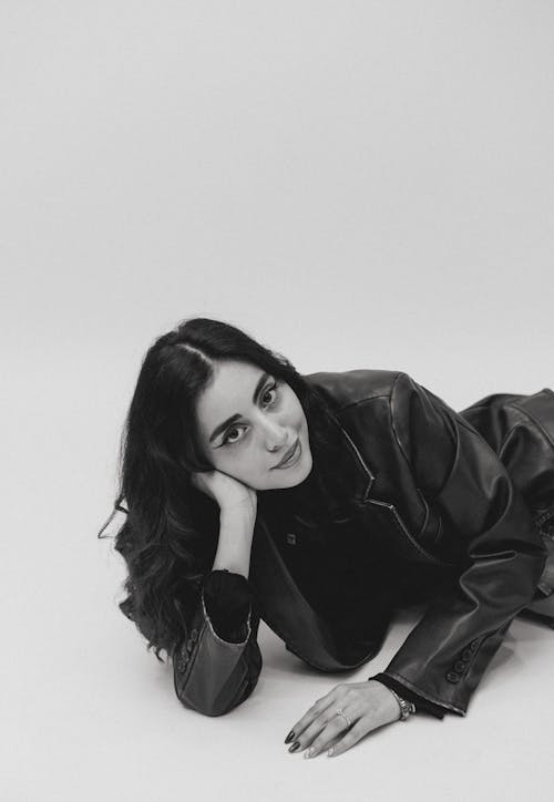 A woman laying on the floor in a black leather jacket