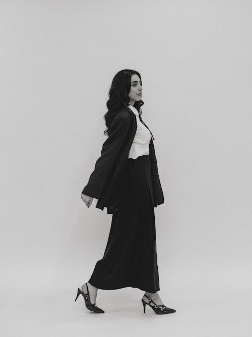 A woman in a black and white photo is standing in front of a wall