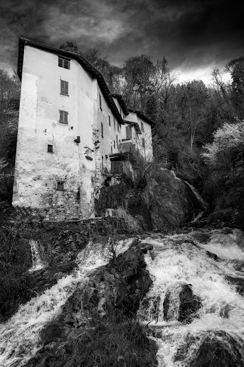 A black and white photo of a waterfall and a building