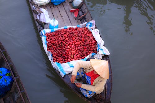 Persona Sentada En El Barco Junto A Verduras Rojas