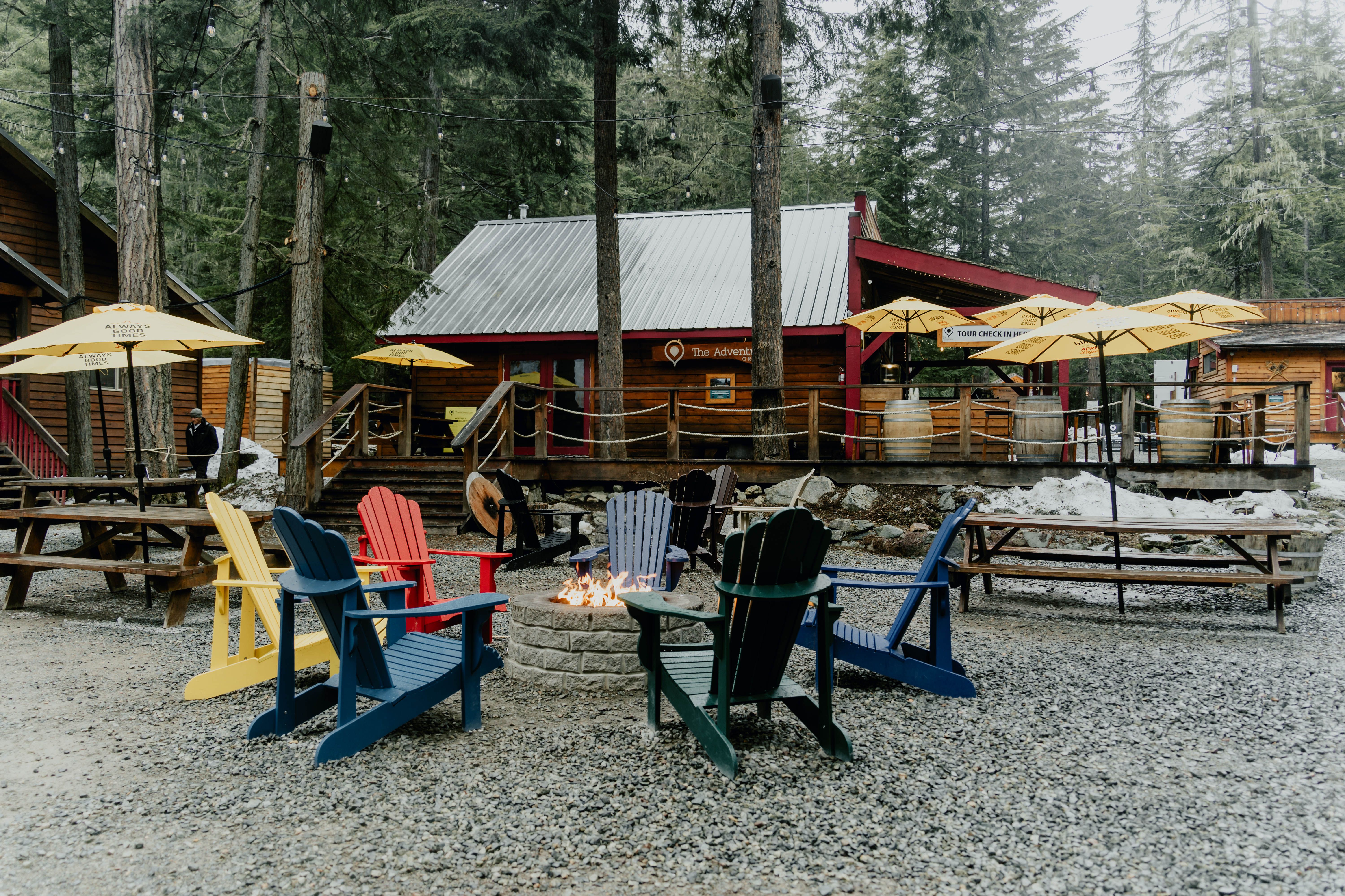 Colorful Adirondack chairs surround a campfire at a cozy Whistler, BC campsite.