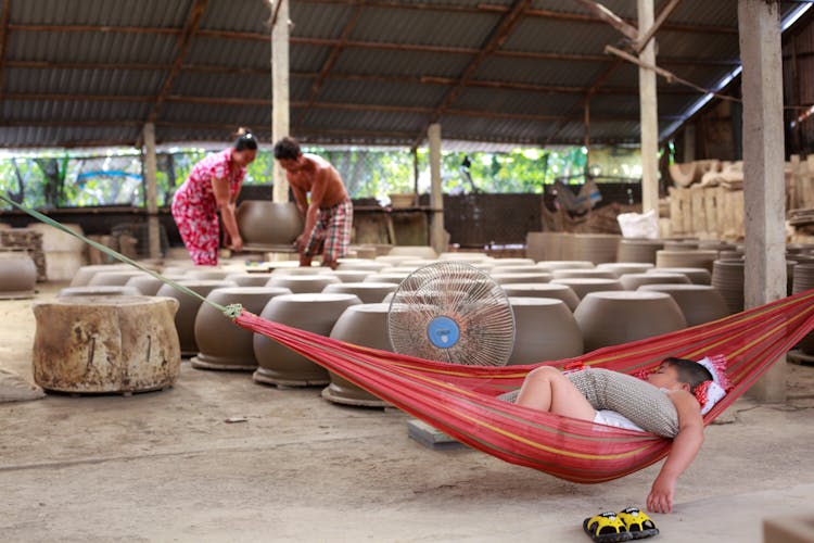 Man Sleeping On Red Hammock Near Clay Pots