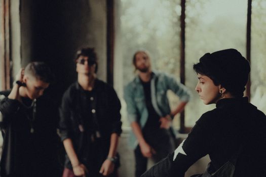 A fashionable group of young adults poses in a dimly lit room, evoking a sense of mystery.