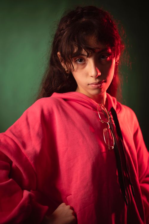 Free Portrait of a serious woman in a pink hoodie with dramatic lighting. Stock Photo