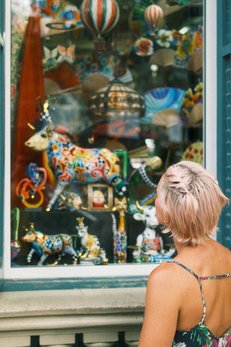 Woman Standing Near Window Of Store With Figurines