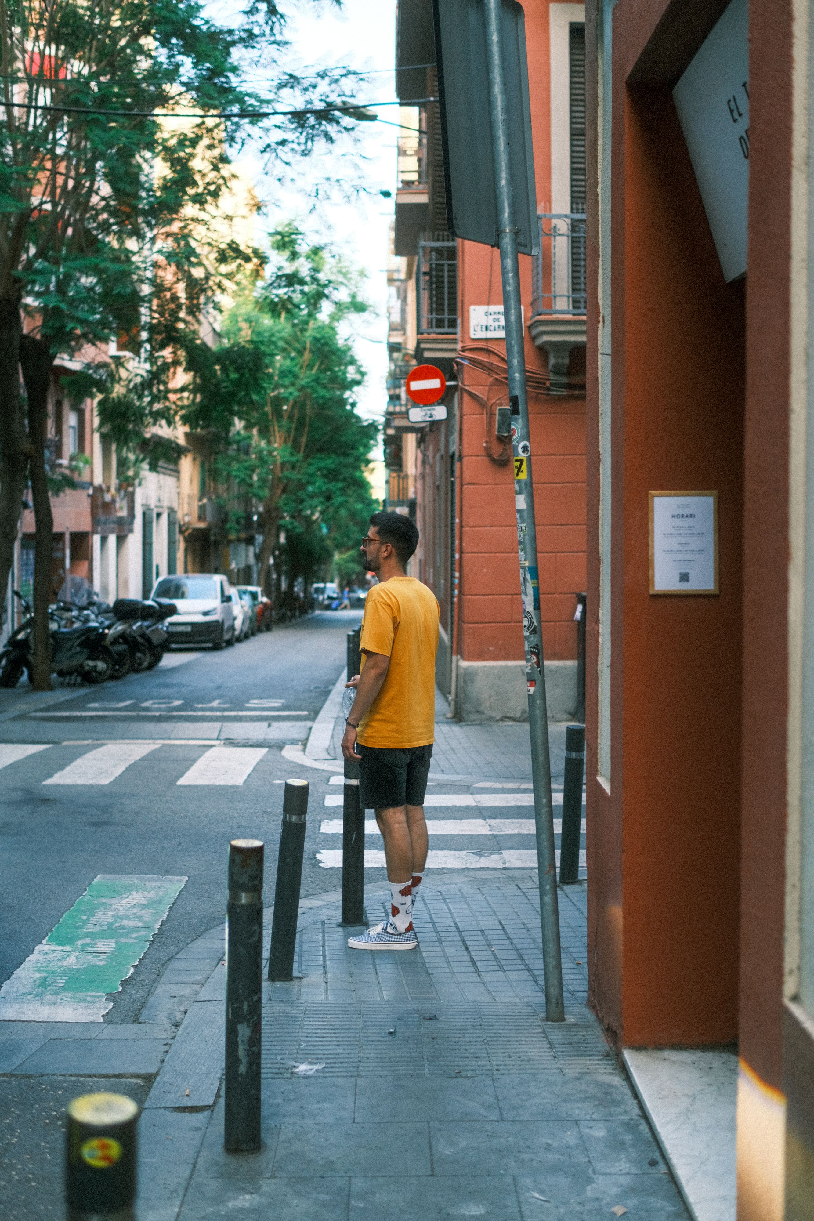 A man stands on a Barcelona street corner, capturing the essence of urban life.