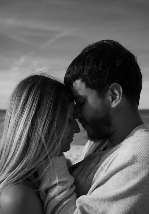 A black and white photo of a couple embracing on the beach