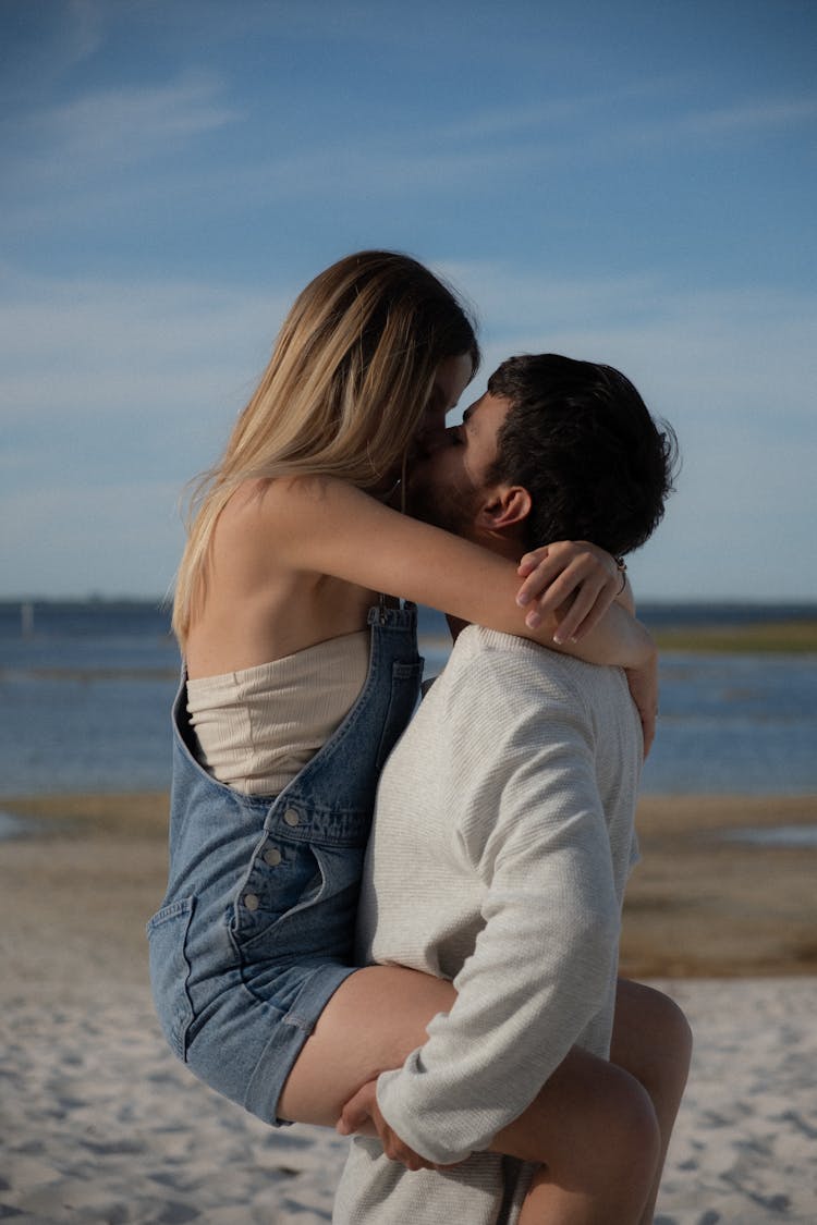 Blonde Woman Hugging And Kissing Man On Beach