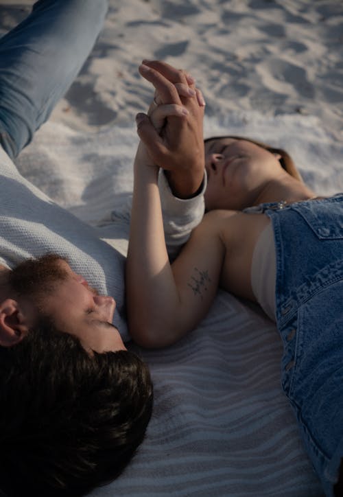 Free A man and woman laying on a blanket on the beach Stock Photo