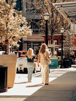 Two women walking on a sunny Atlanta street in spring, surrounded by urban architecture.