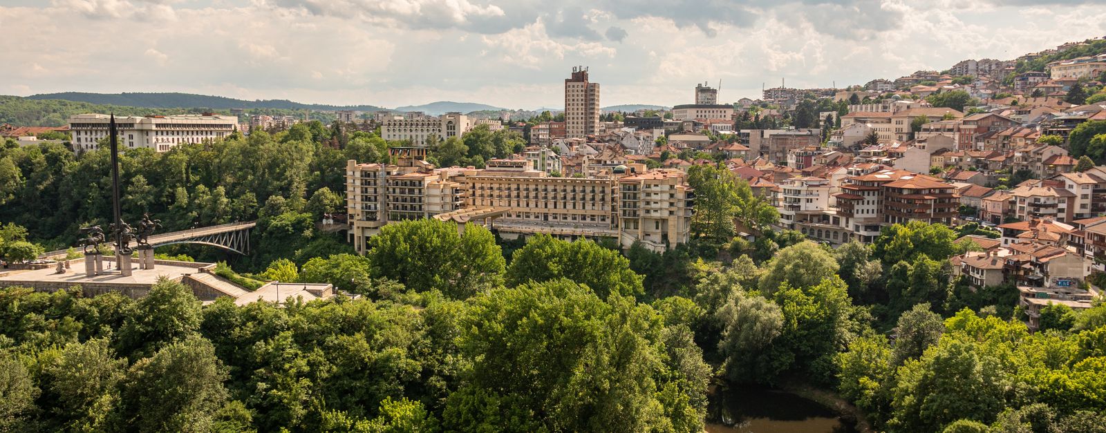 Stunning aerial view of Veliko Tarnovo cityscape with lush greenery, iconic buildings, and river in Bulgaria.