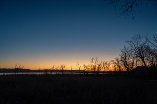 A tranquil sunset at Weaver Lake, Minnesota, with silhouetted trees against a glowing sky.