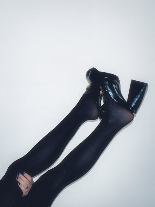 A woman's legs are shown in black tights and high heels