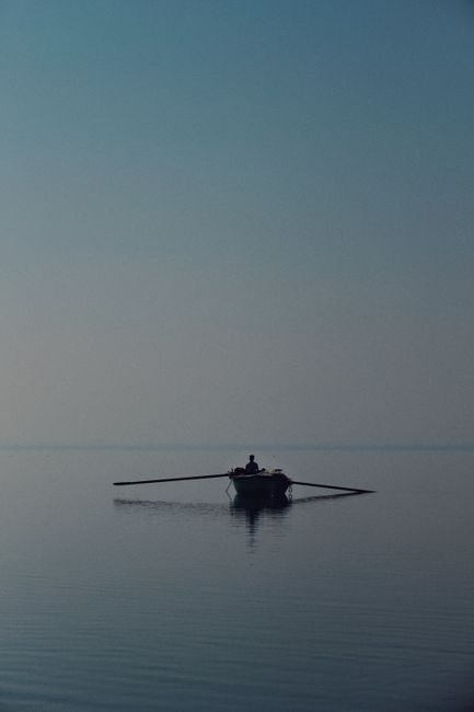 A solitary boat silhouette with oars on tranquil waters at sunset in Fayyum Oasi, Egypt.