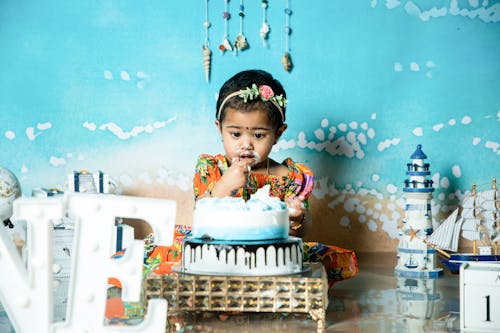 Free A little girl is sitting in front of a cake with a blue and white sign Stock Photo