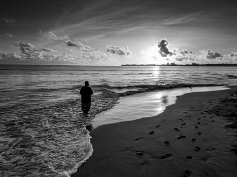 Black and white photo of a person standing on Río Grande beach during sunset.
