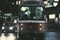 夜间，城市街道上行驶着公交车和汽车，在降雪中营造出忧郁的城市景象