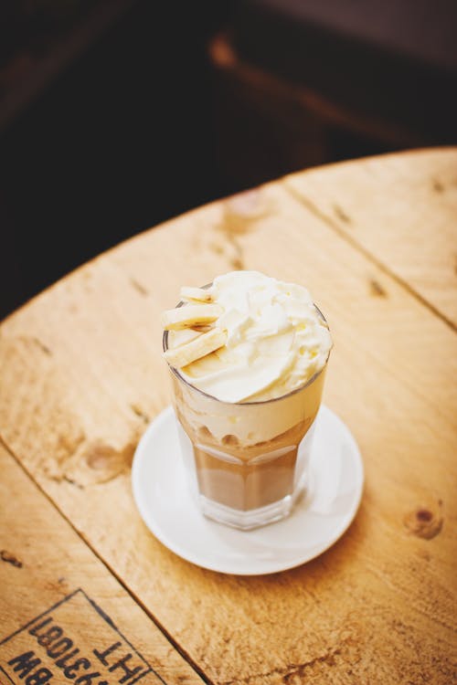 Photo of Clear Glass Cup With Whip Cream on Top Place on Saucer