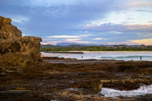 Free Scenic view of Currumbin Beach, capturing rocks and people at sunset. Stock Photo