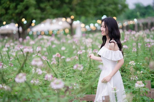 A woman in a white dress walking through a field of flowers