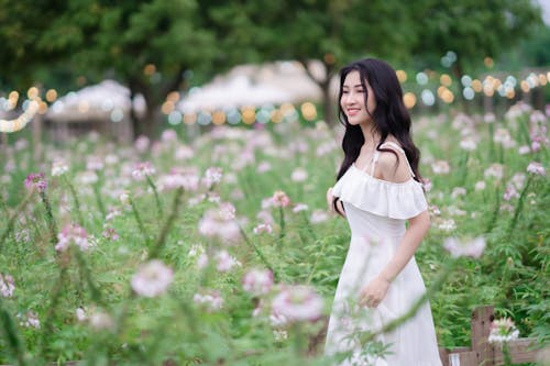 A woman in a white dress walking through a field of flowers