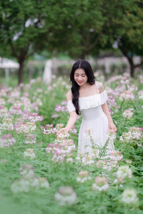 A woman in a white dress is standing in a field of flowers