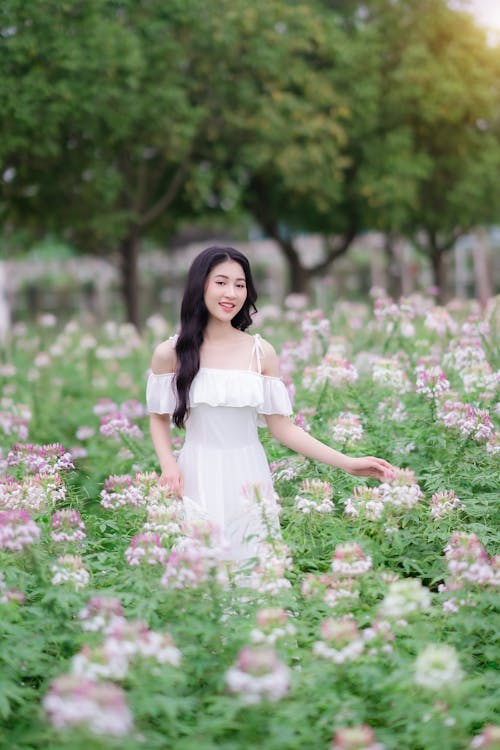 A woman in a white dress is standing in a field of flowers