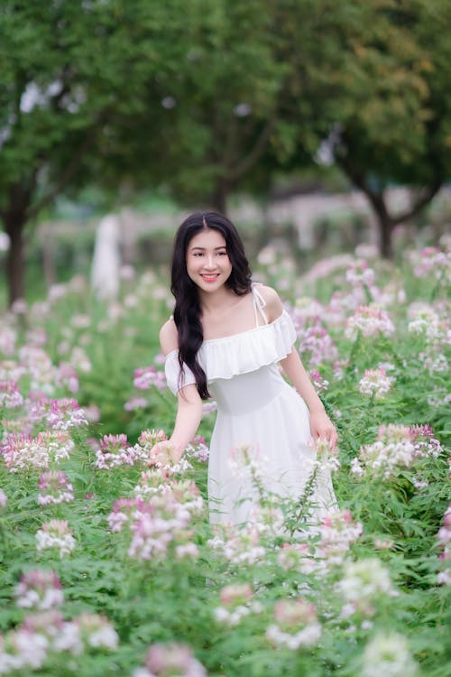 A woman in a white dress is standing in a field of flowers