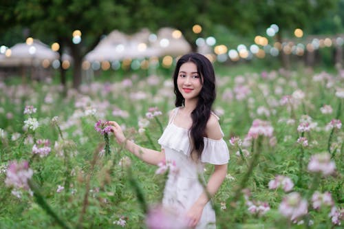 A woman in a white dress is standing in a field of flowers