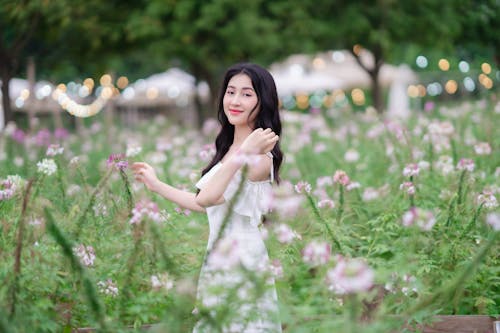 A woman in white dress standing in a field of flowers