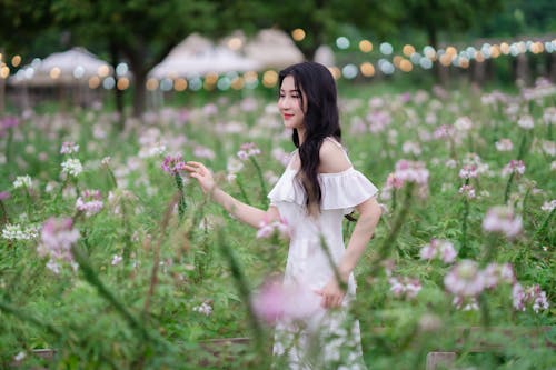 A woman in a white dress is standing in a field of flowers