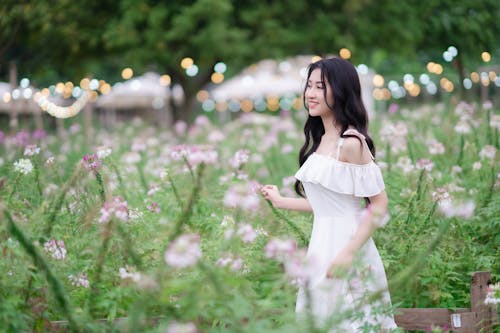 A woman in a white dress walking through a field of flowers