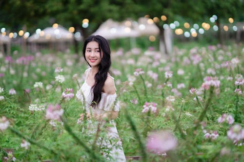 A woman in a white dress is standing in a field of flowers