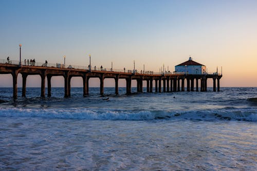 Free A pier with waves crashing on the shore at sunset Stock Photo