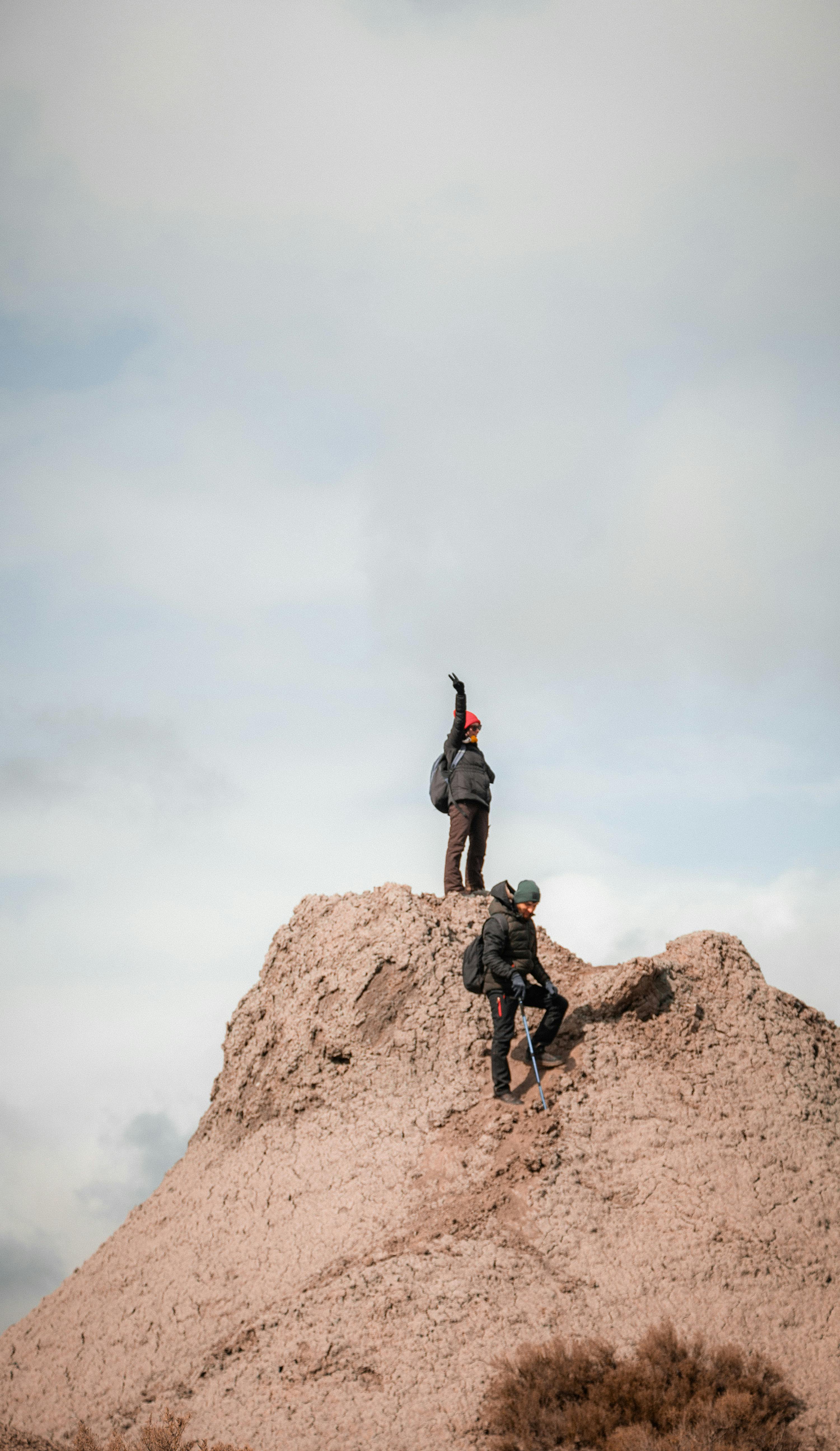Two hikers reaching the summit of a rocky peak, symbolizing adventure and achievement.