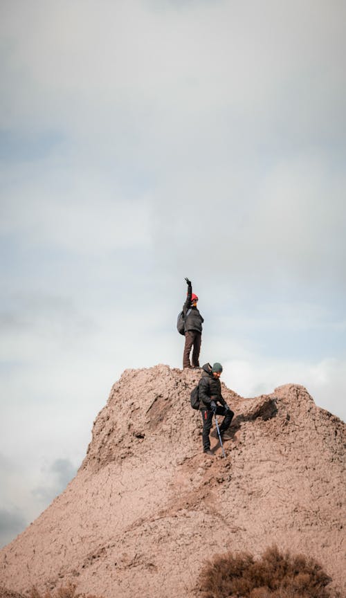 Two people standing on top of a hill with one holding a flag