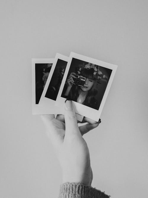 A person holding up two polaroids in their hand