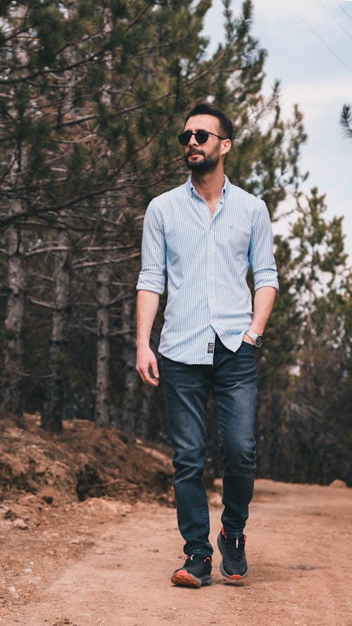 Man in Shirt and Sunglasses Walking on Dirt Road in Forest