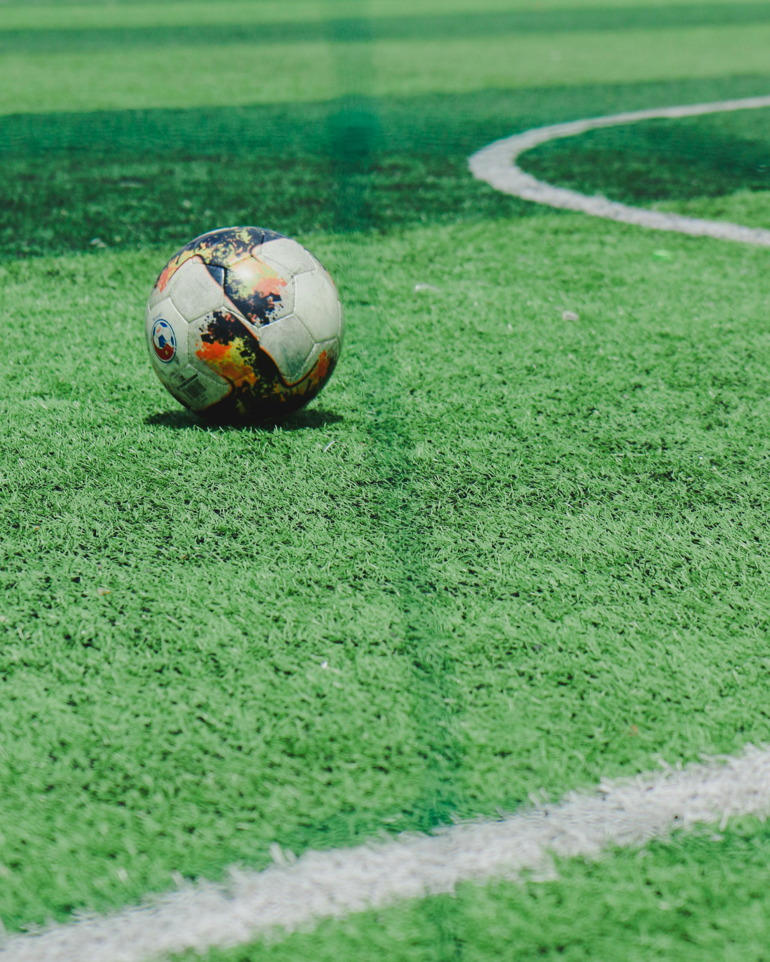 A soccer ball on a green field with a white line · Free Stock Photo