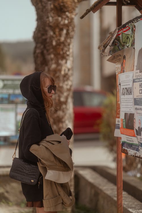 Free A woman in a hoodie looking at a poster Stock Photo