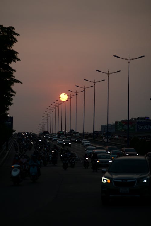 A sunset over a busy highway with cars and motorcycles