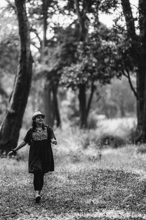 Free A young woman wearing a fedora walks joyfully through a lush forest in Wayanad, India. Stock Photo