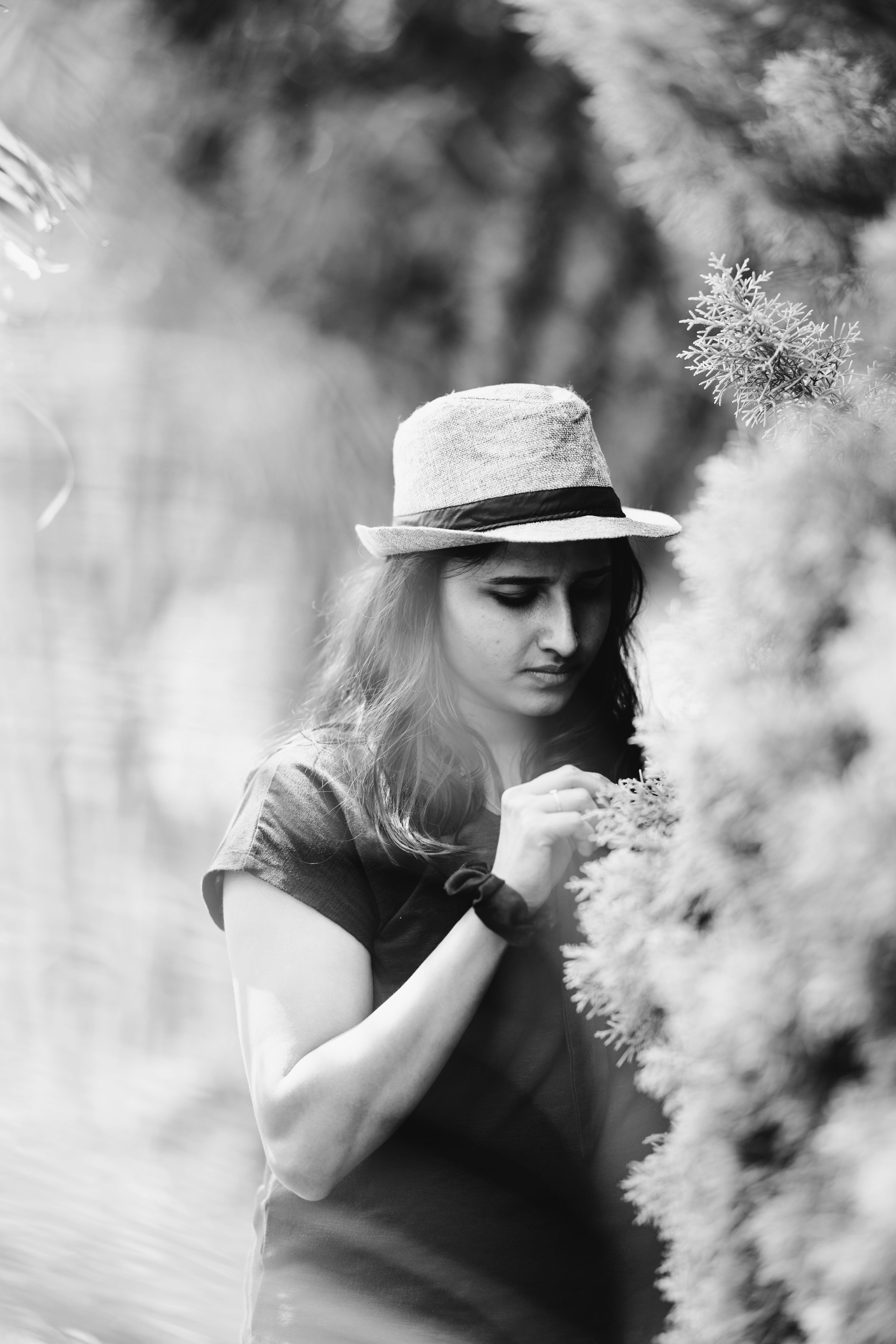 A contemplative woman in a hat enjoys a serene garden moment in Wayanad, India.
