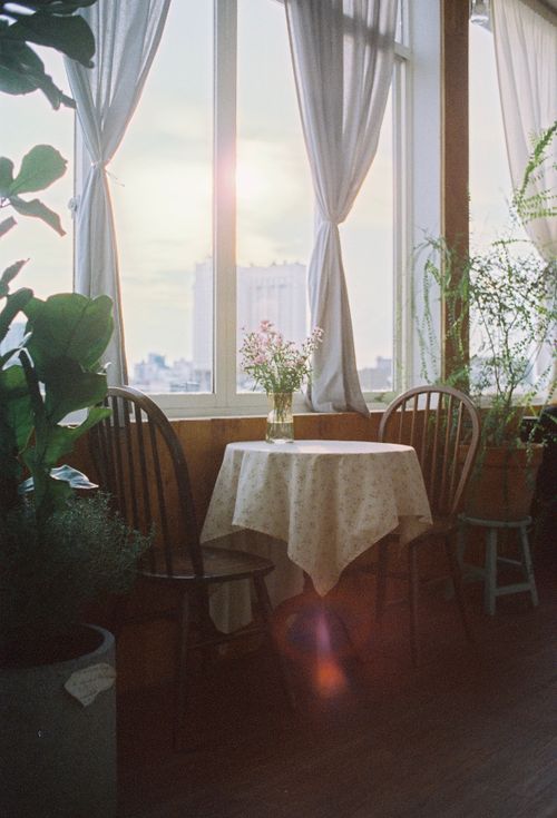 Free A serene dining nook with a cityscape view and floral arrangement, perfect for relaxation. Stock Photo
