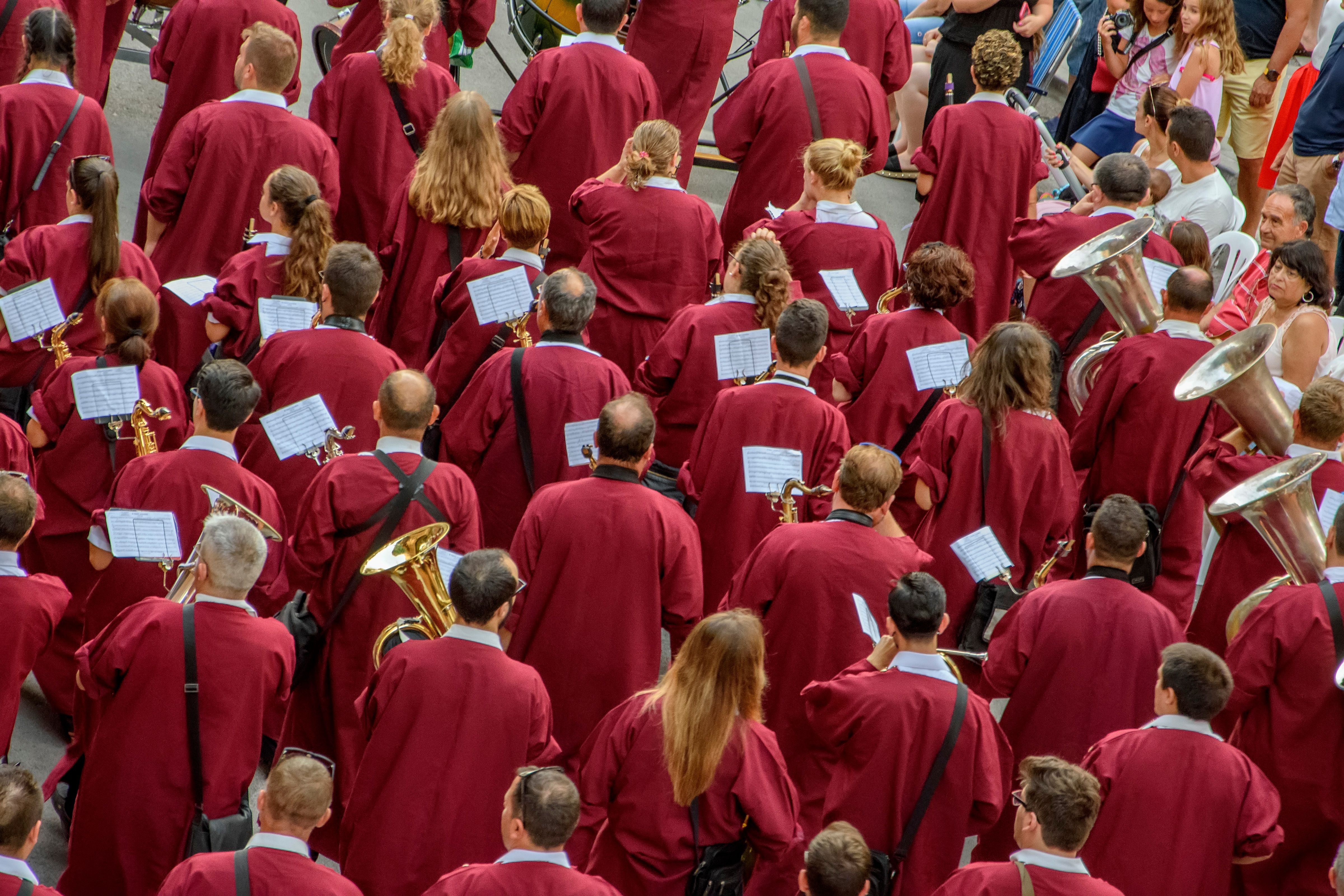 A vibrant parade of musicians in red uniforms performing outdoors in Alicante, Spain.