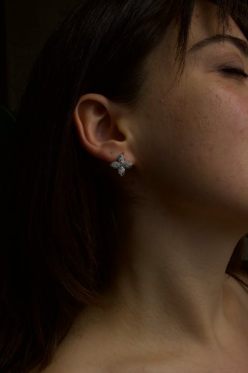 A woman wearing a pair of earrings with a cross on them