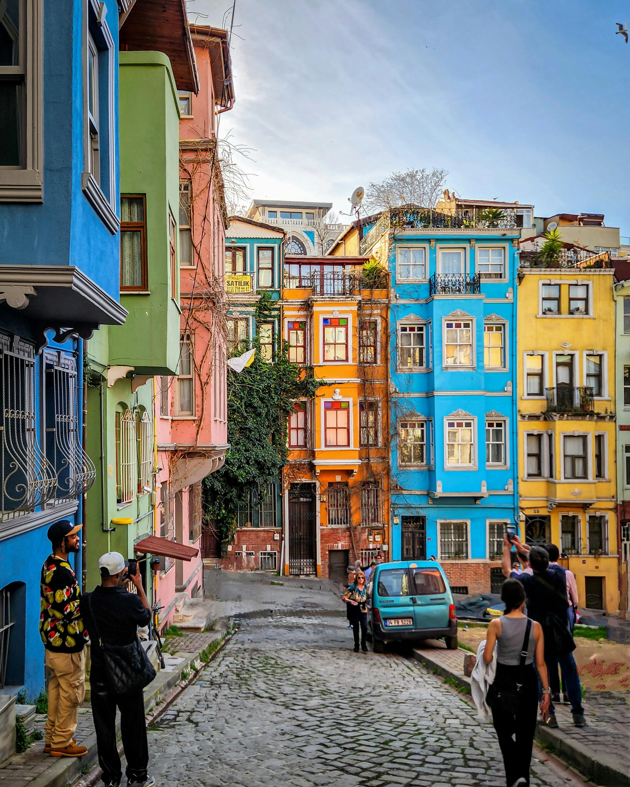 Tourists photographing vibrant townhouses in Istanbul's Balat neighborhood.