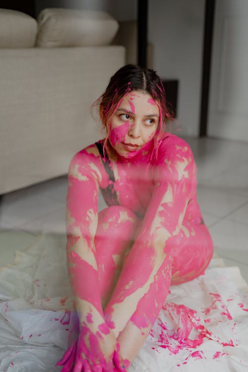 Free A woman with pink paint on her body sitting on the floor Stock Photo