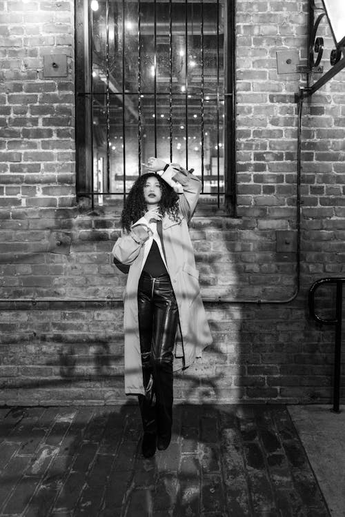 Teenage Girl Leaning on Brick Wall at Night