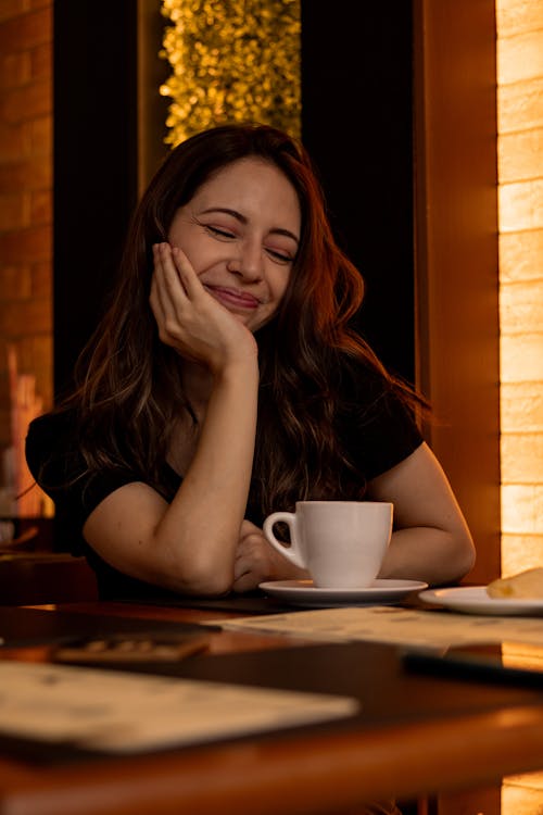 Free A woman sitting at a table with a cup of coffee Stock Photo